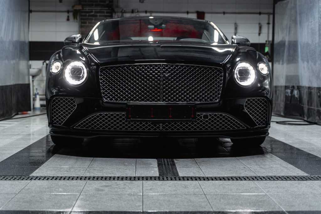 Front view of a sleek black Bentley inside a car wash, showcasing elegance and luxury.