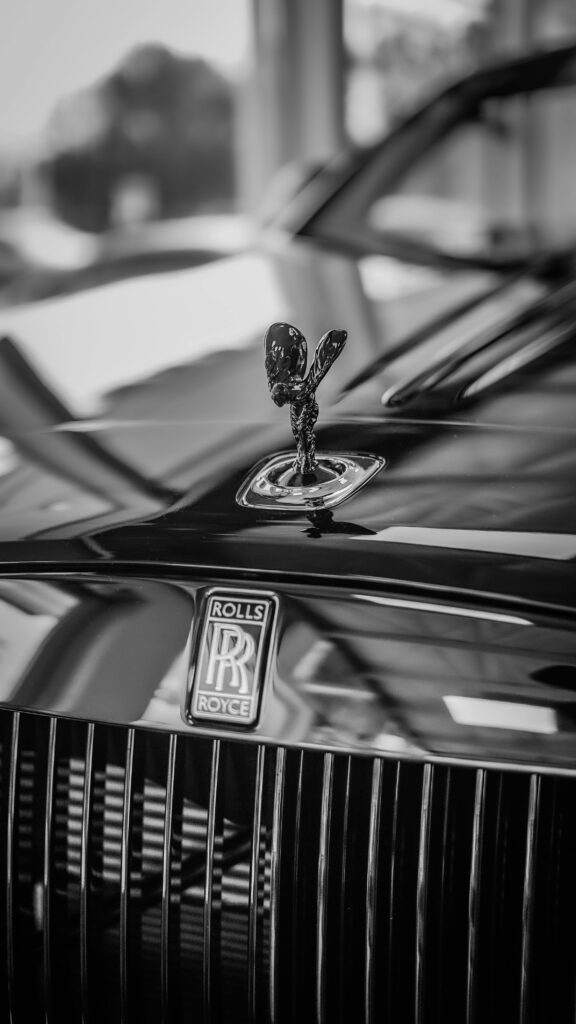 Close-up of a Rolls Royce emblem on a luxury car in grayscale. Elegant vintage style.